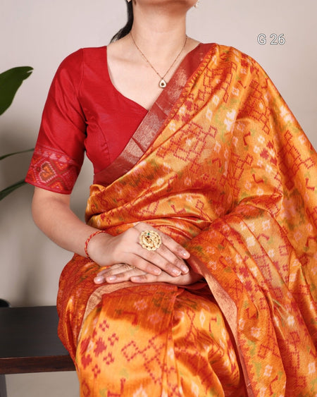 Person wearing a red blouse with an orange saree, sitting on a chair.