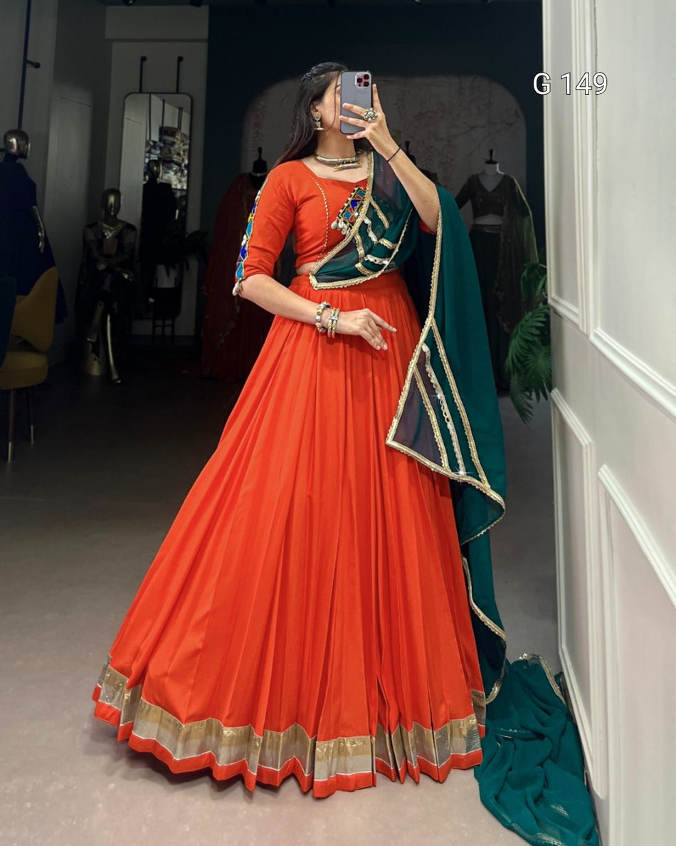Woman in an orange and green traditional outfit taking a mirror selfie.
