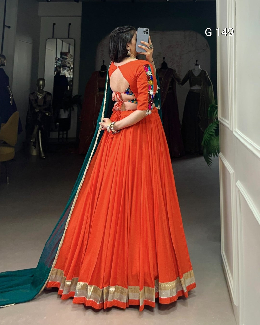 Person wearing an orange saree with a blue blouse in a store setting.