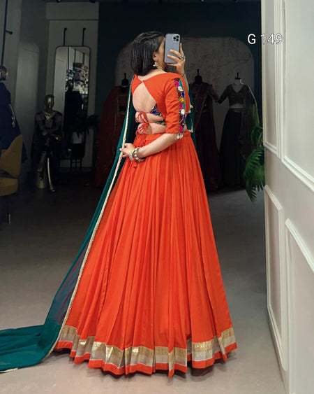 Person wearing an orange saree with a blue blouse in a store setting.