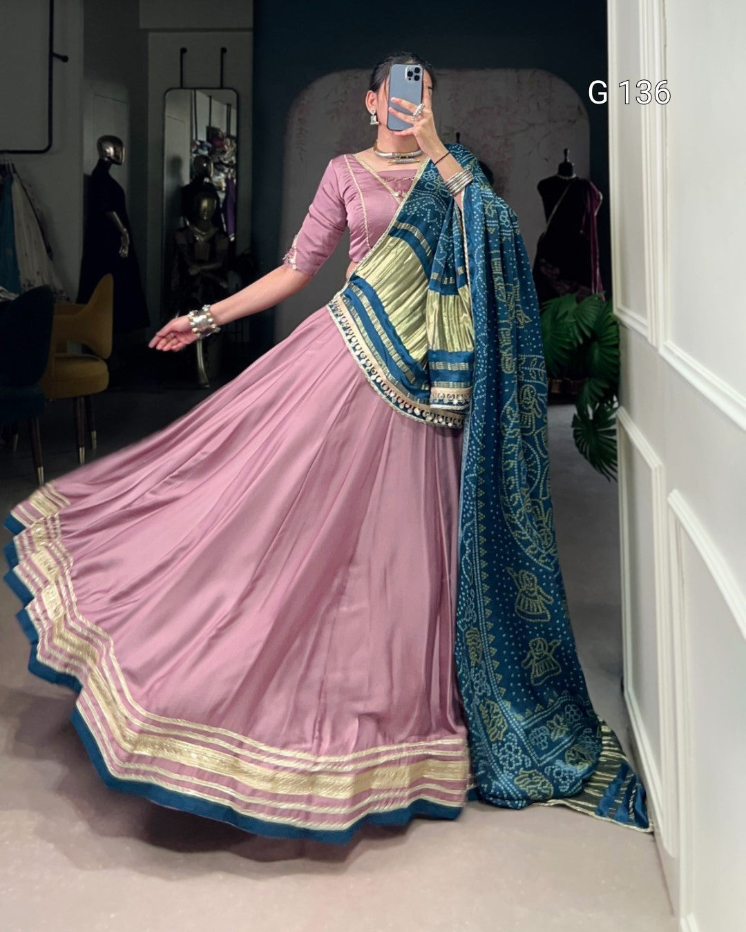 Person wearing a pink saree with blue and green border in a room.