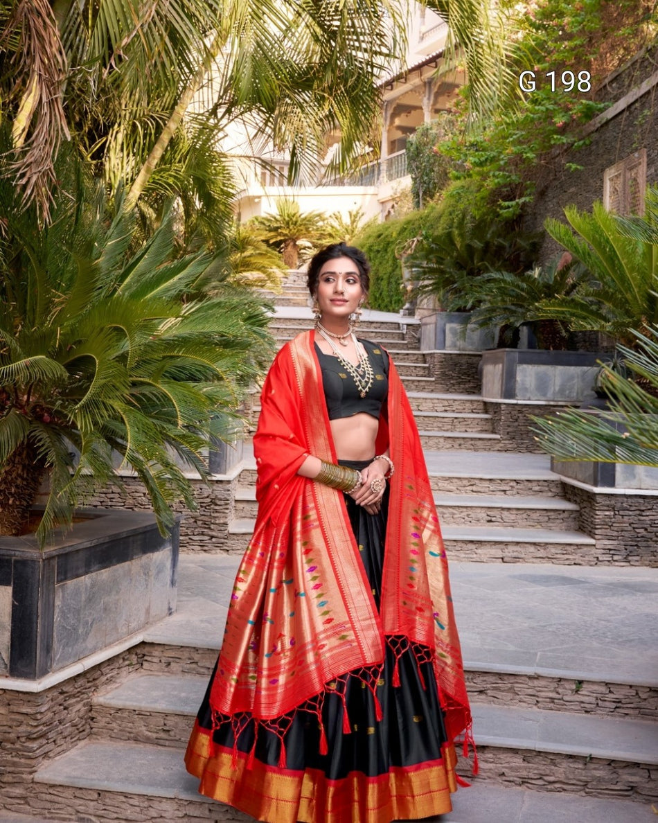 Woman in a red and black traditional outfit standing outdoors with greenery.