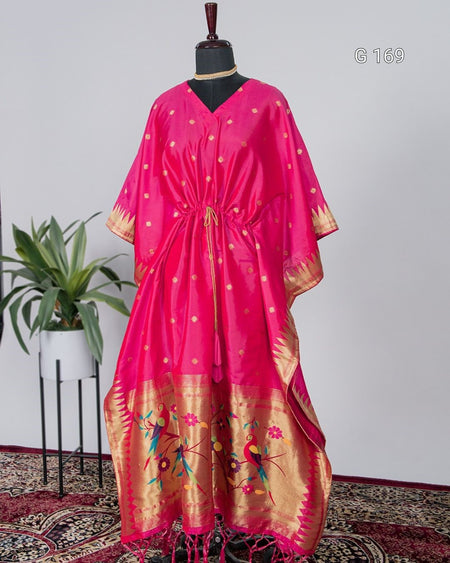 Pink and gold traditional dress on a mannequin with a plant in the background