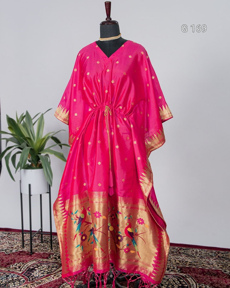 Pink and gold traditional dress on a mannequin with a plant in the background