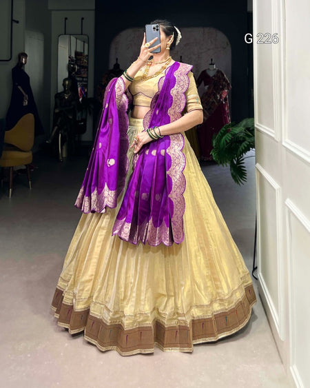 Woman wearing a traditional outfit with a purple dupatta in a room setting.