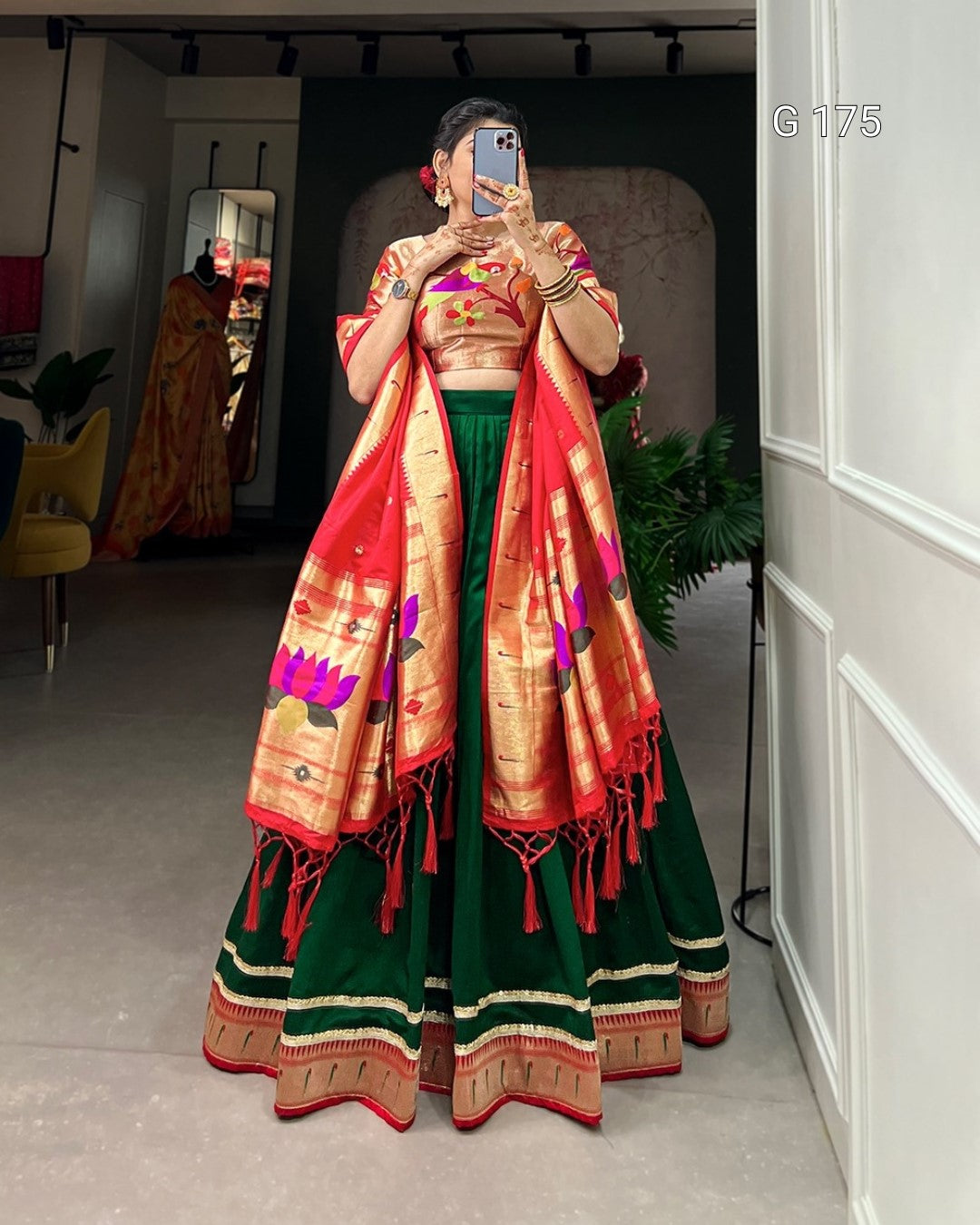 Person wearing a traditional outfit with a red and green saree in a room.