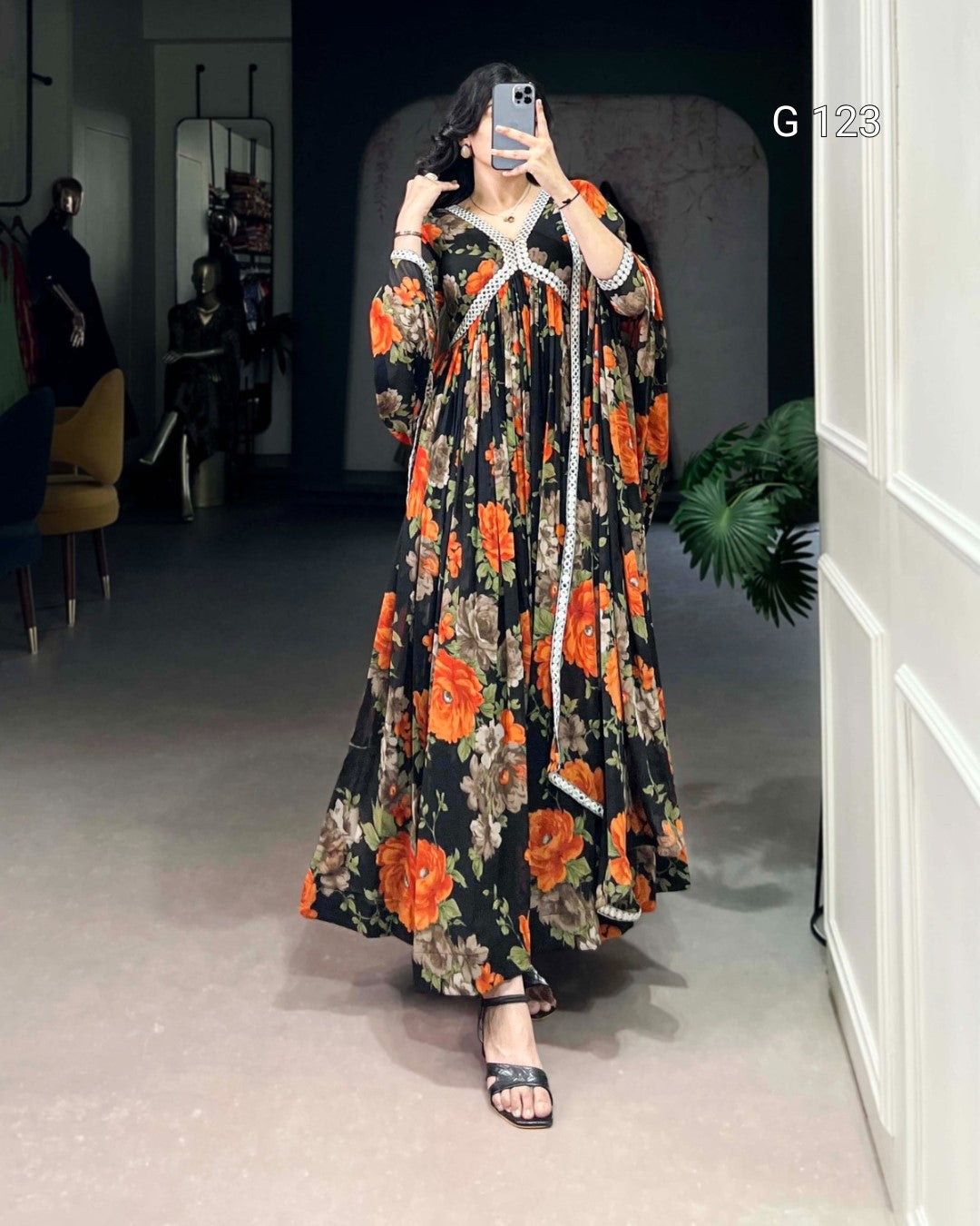 Person wearing a floral dress with orange flowers in a room.