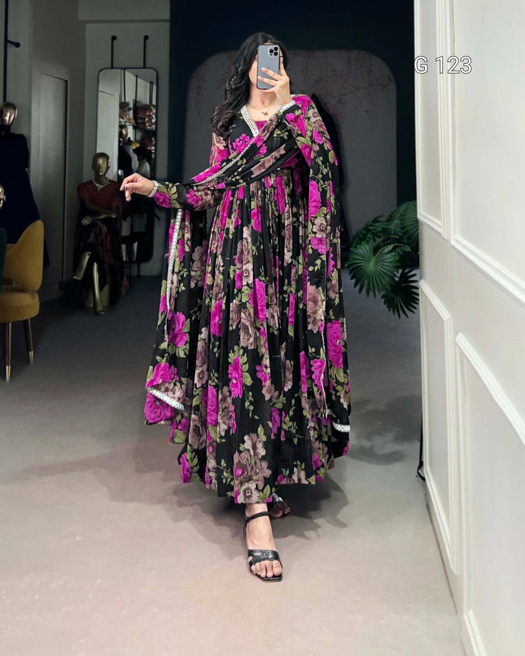 Woman wearing a floral dress in a room with a mirror and chair.