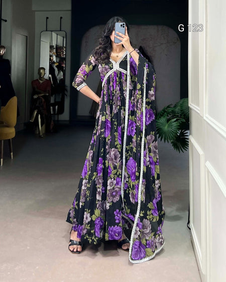 Woman wearing a black floral dress with purple flowers in a room.
