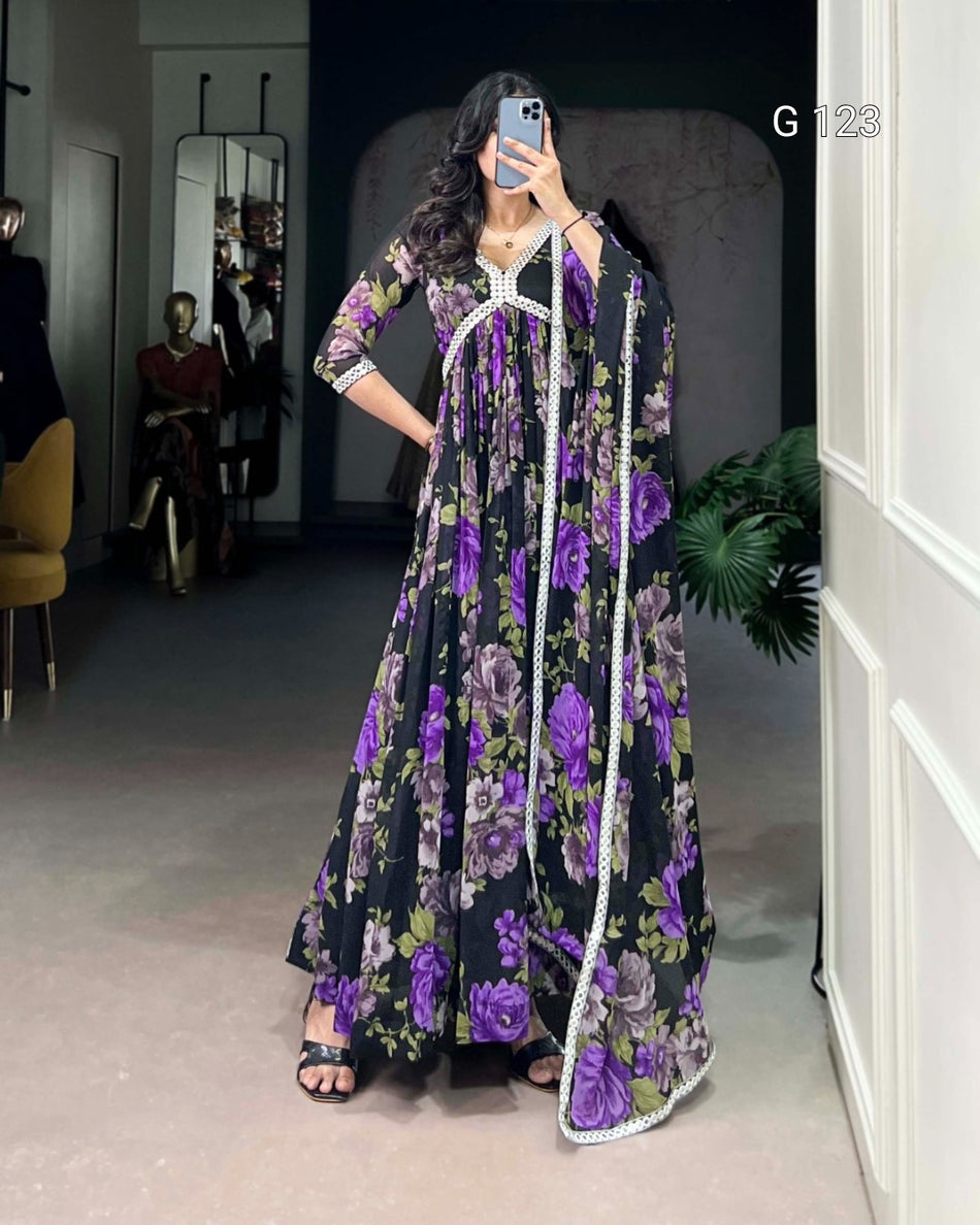 Woman wearing a black floral dress with purple flowers in a room.