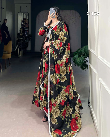 Woman wearing a long floral dress in a room with a mirror and plant.