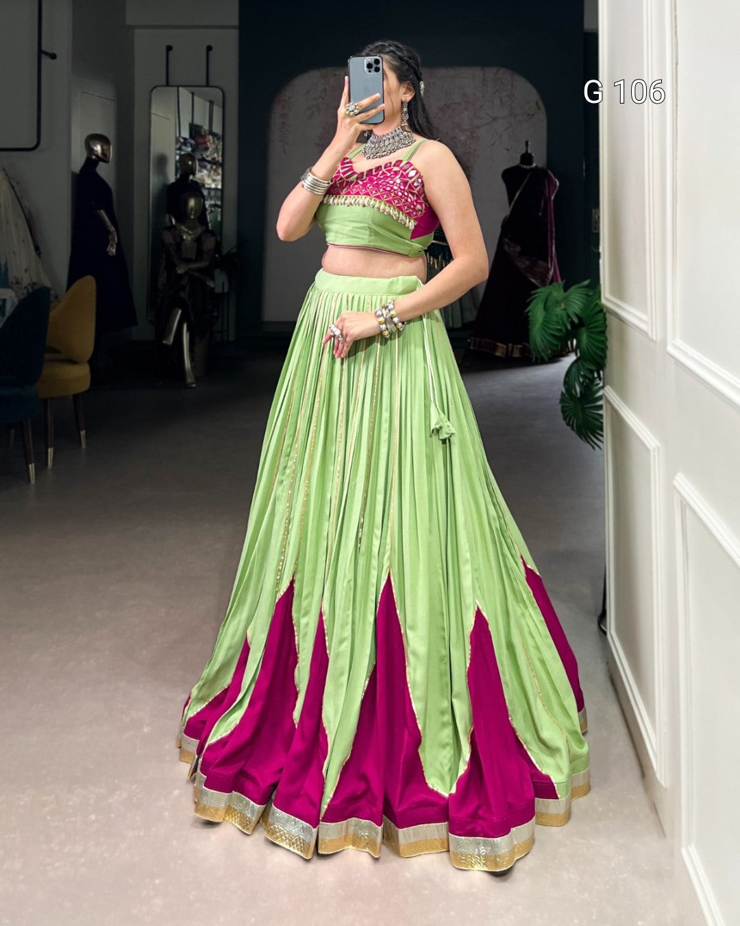 Person wearing a green and pink traditional outfit taking a mirror selfie.