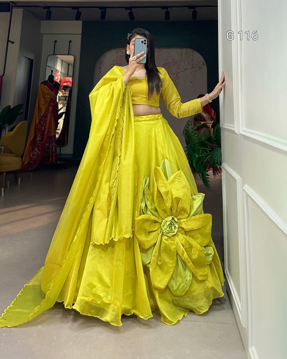 Person wearing a bright yellow traditional outfit with a large flower detail, standing in a room.