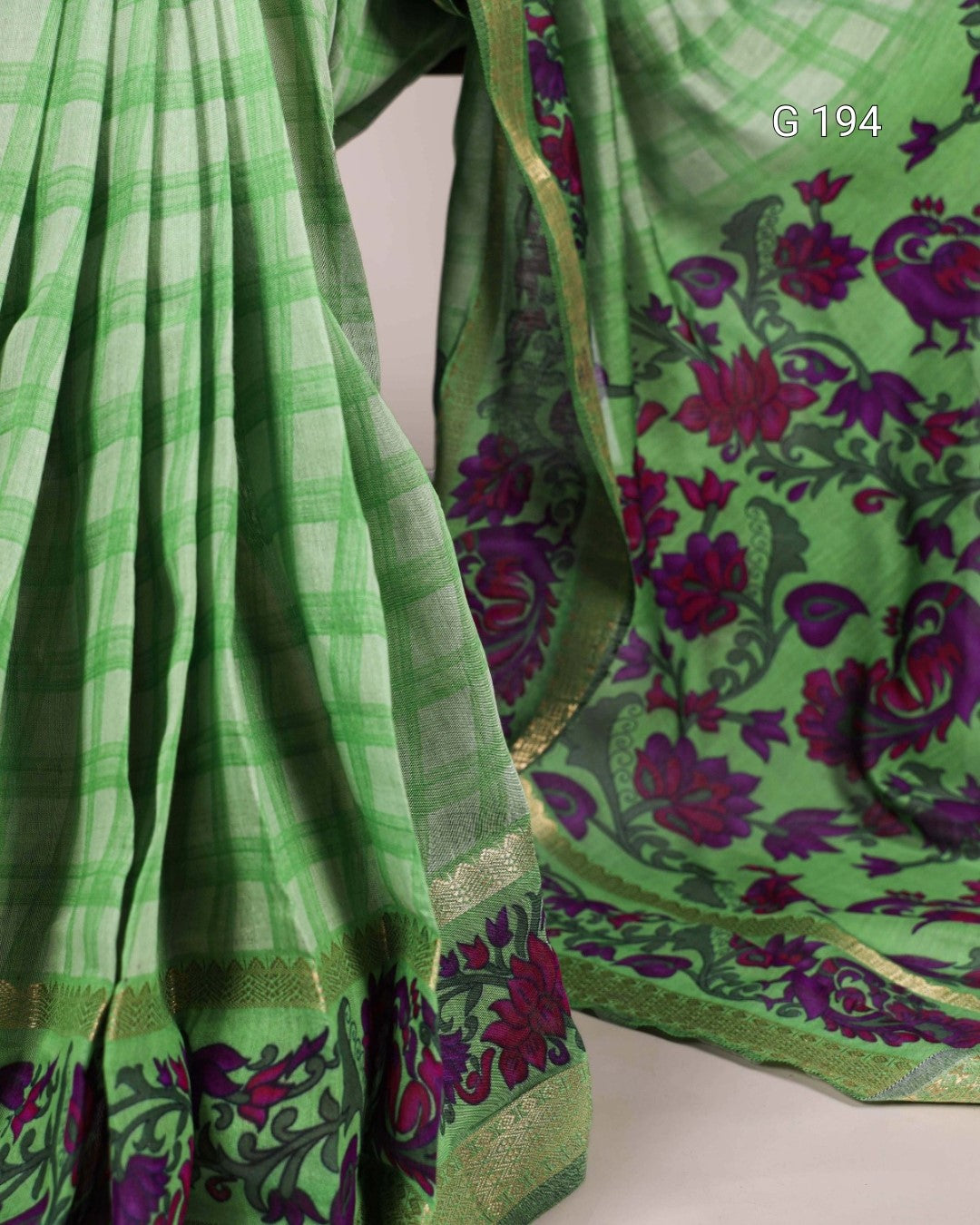 Green saree with floral patterns on a plain background