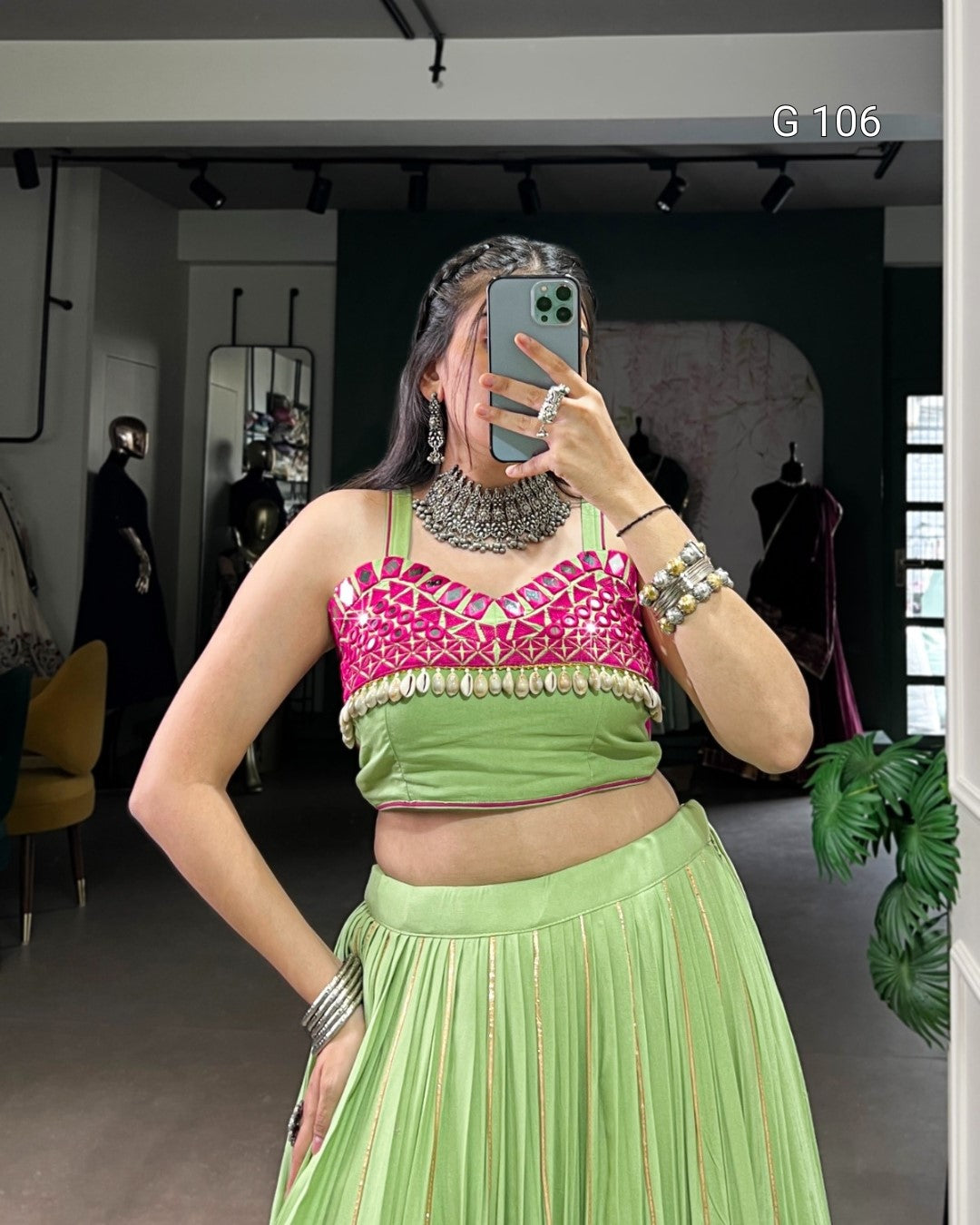 Person wearing a green and pink traditional outfit with jewelry in a mirror selfie.