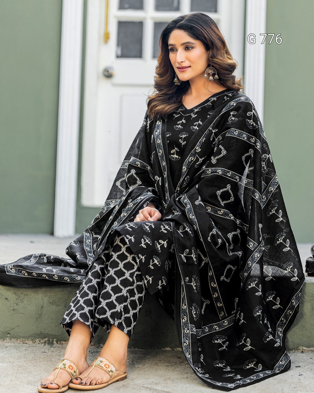 Woman wearing a black and white patterned outfit sitting on a step.