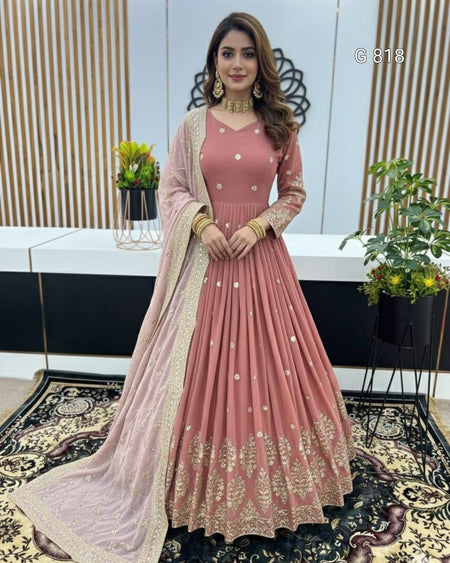 Woman in a pink traditional outfit with gold embroidery in an indoor setting.