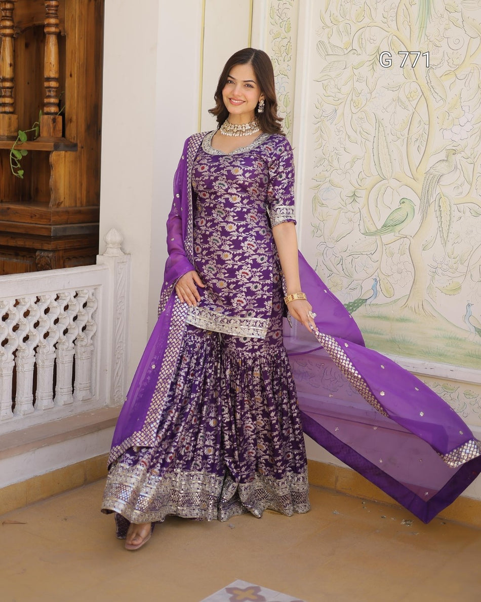 Woman wearing a purple traditional outfit with a matching dupatta in an indoor setting.
