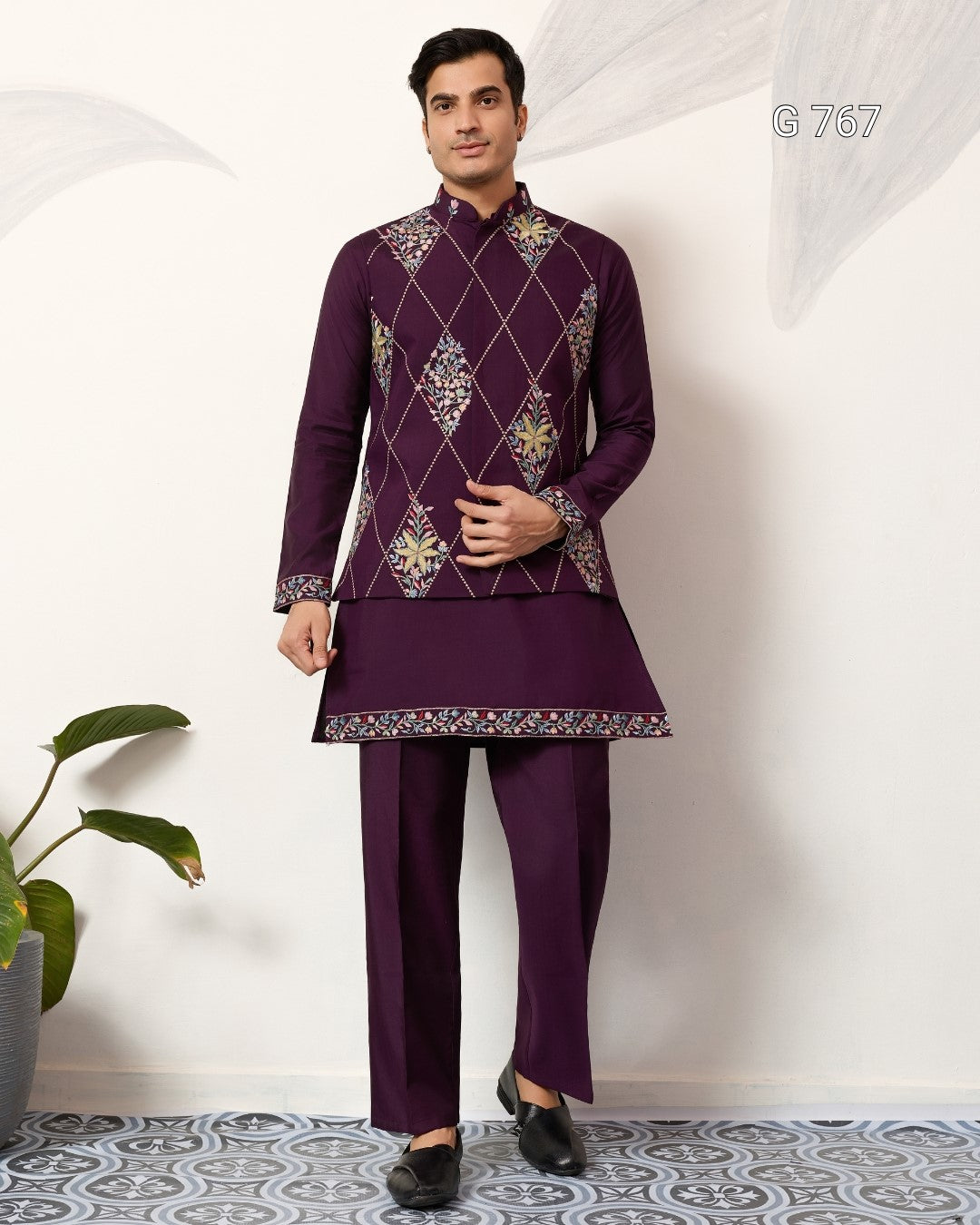 Man wearing a purple embroidered traditional outfit on a white background