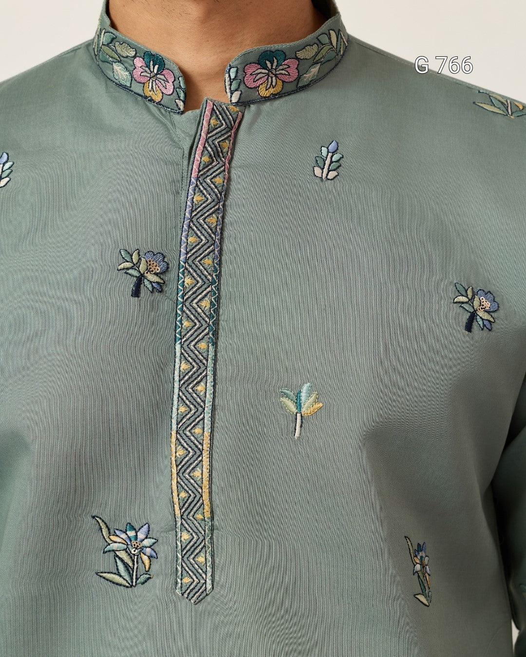 Green embroidered shirt with floral patterns on a plain background