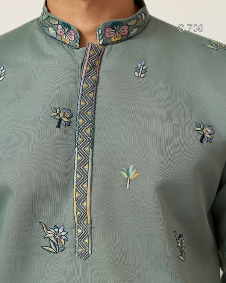 Green embroidered shirt with floral patterns on a plain background