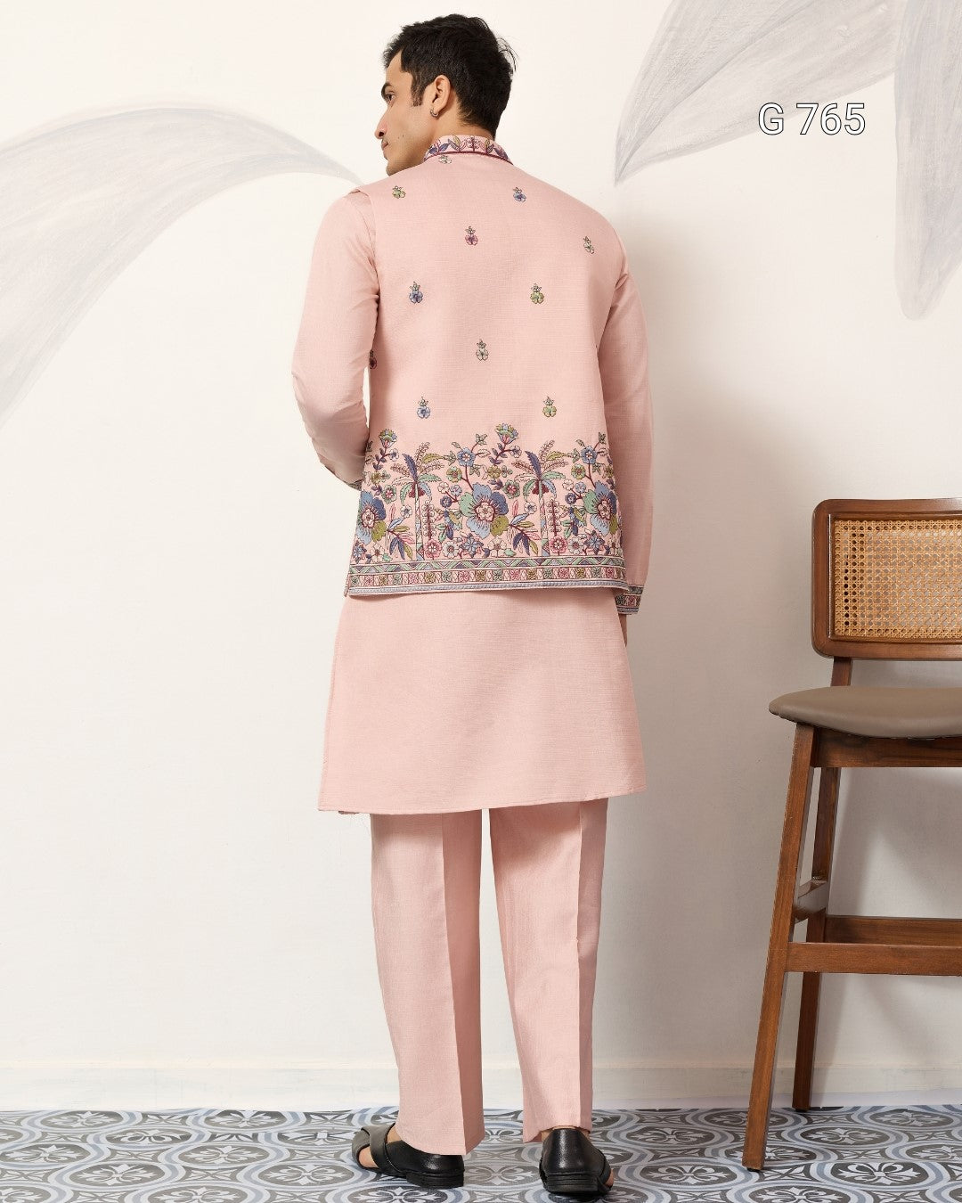 Person wearing a pink traditional outfit with floral embroidery in a minimal setting.