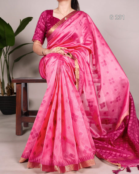 Person wearing a bright pink saree with a subtle pattern, sitting on a chair.
