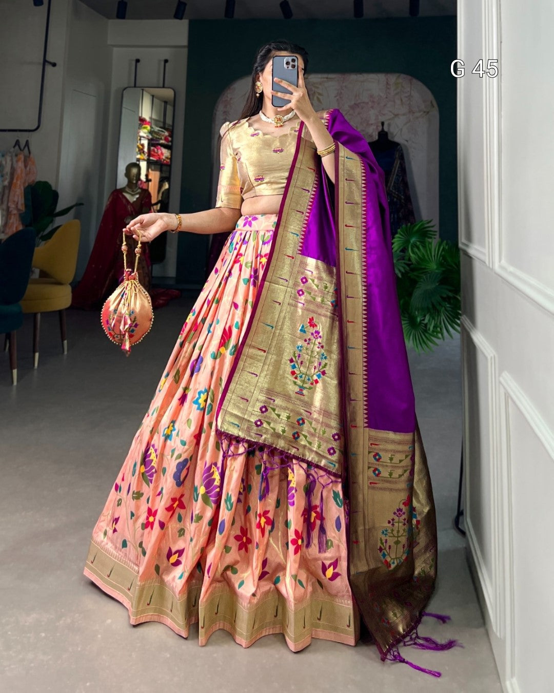 Person wearing a traditional outfit with a pink and purple saree in an indoor setting.