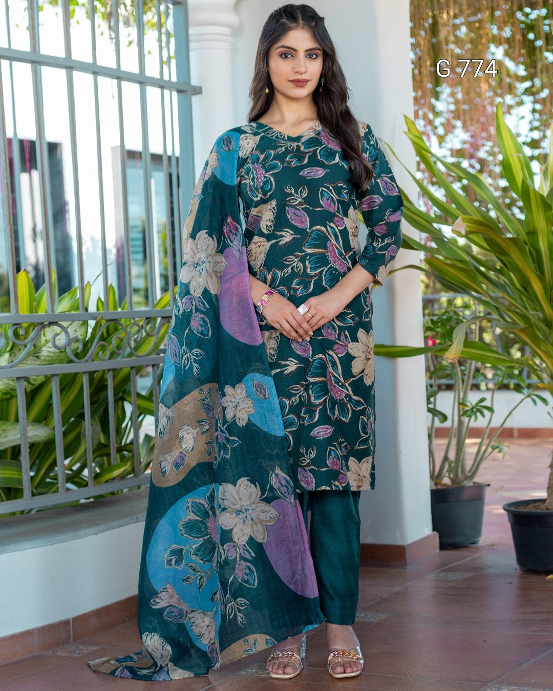 Woman wearing a floral dress with a decorative dupatta in an outdoor setting.
