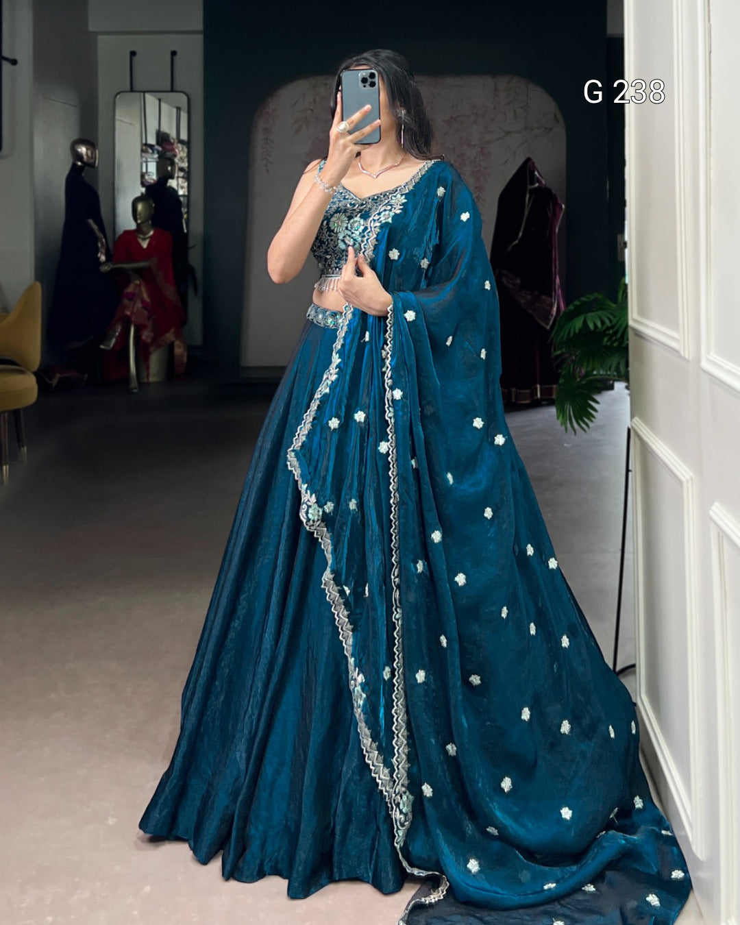 Person wearing a blue embroidered gown taking a mirror selfie.