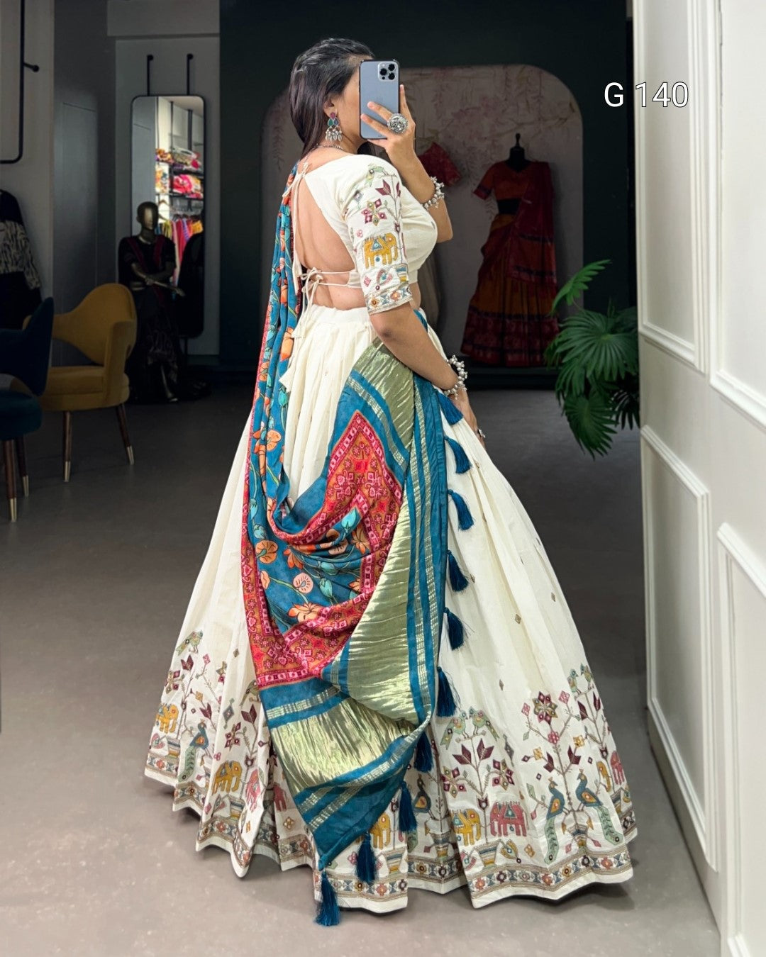 Woman in a traditional outfit with a colorful saree in a room setting.