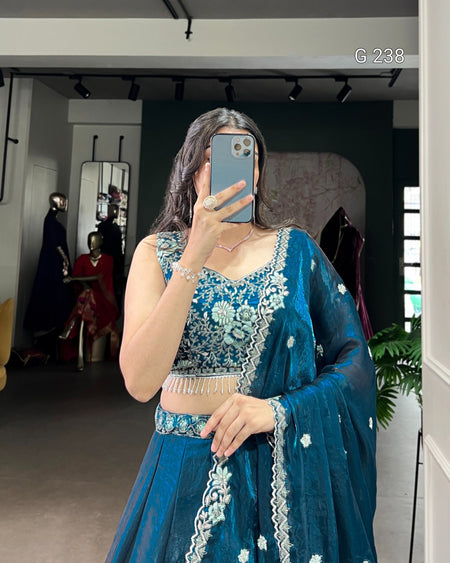 Person wearing a blue embroidered traditional outfit taking a mirror selfie.