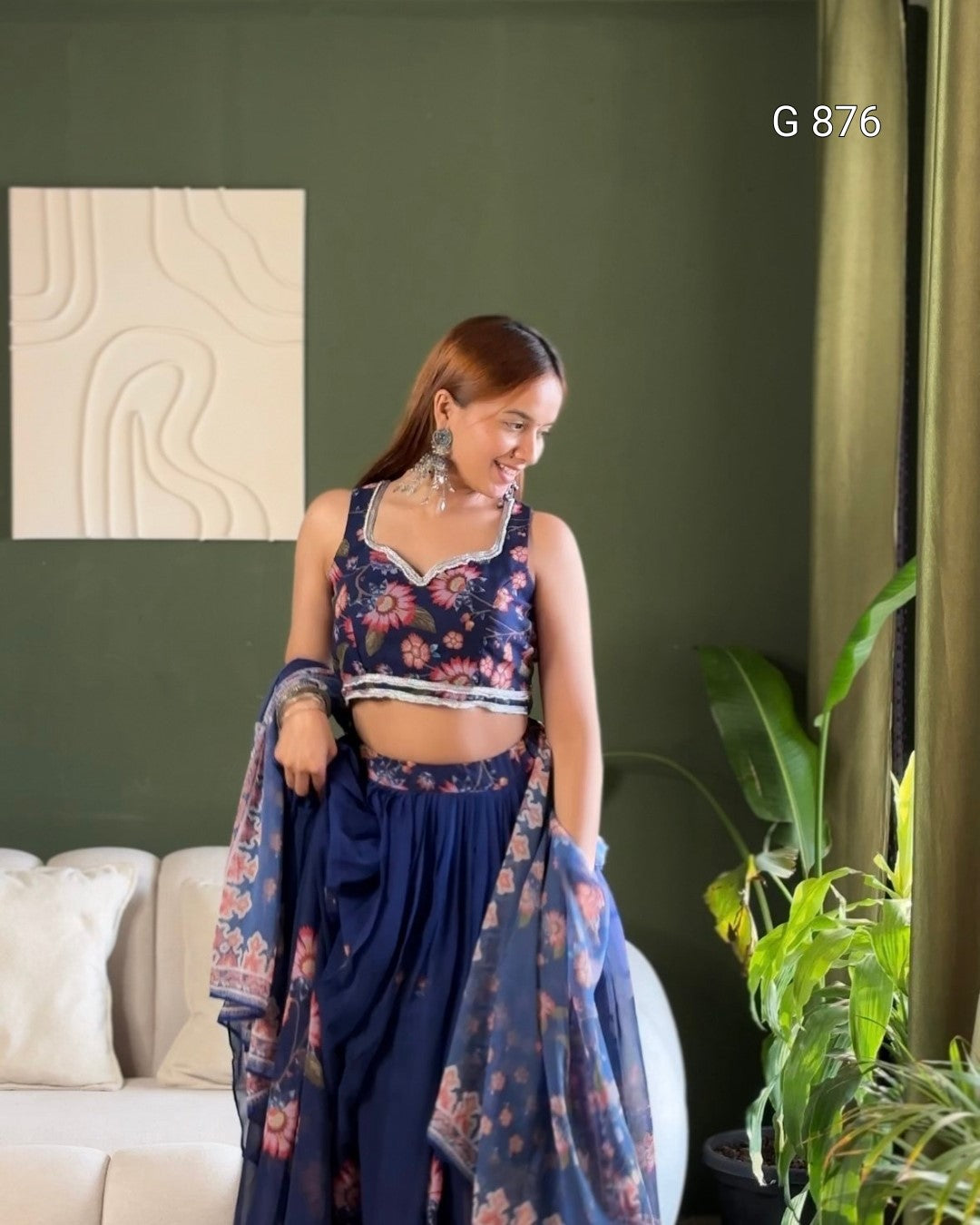 Woman in a floral dress standing in a living room with green walls and a plant.