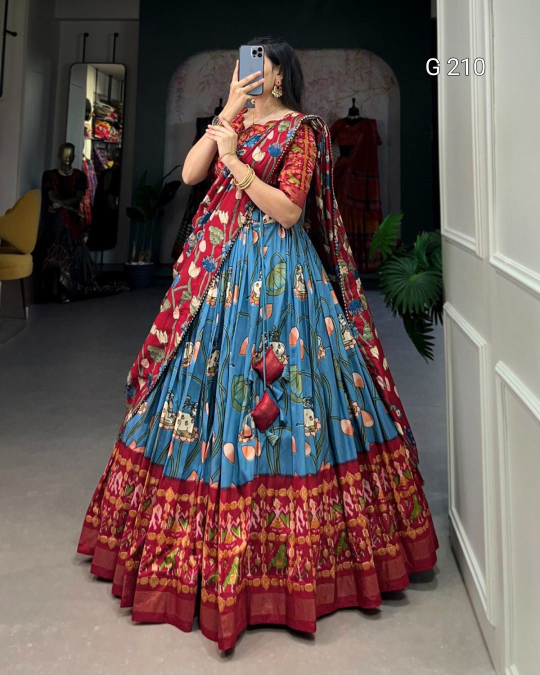 Person wearing a colorful traditional outfit with a blue and red patterned dress in a room.