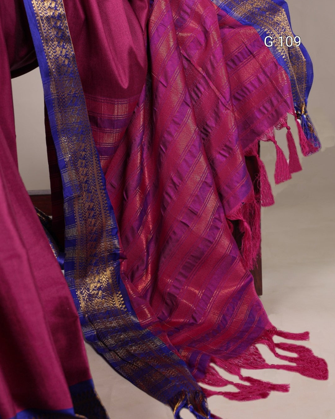 Red and blue patterned fabric with tassels on a plain background