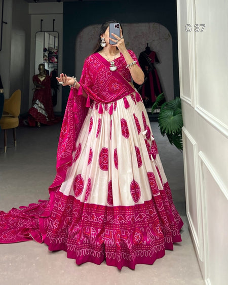 Woman wearing a pink and white traditional outfit with a long train, standing in a room.