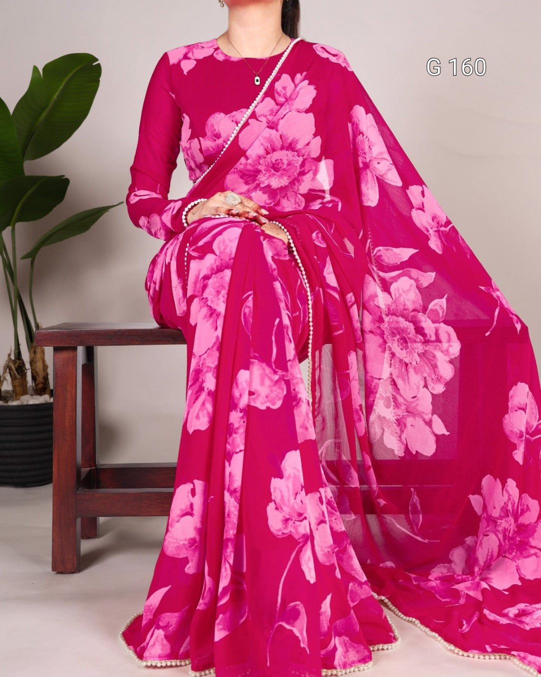 Person wearing a pink floral saree with a white background