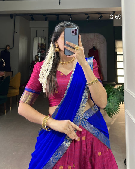 Woman in a blue and pink saree taking a mirror selfie indoors.
