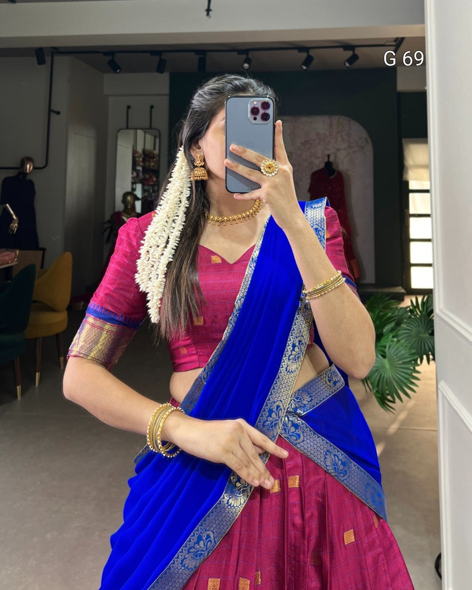 Woman in a blue and pink saree taking a mirror selfie indoors.