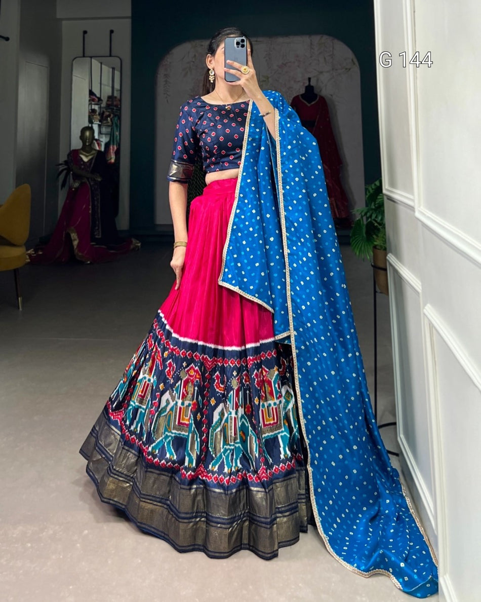 Person wearing a traditional outfit with a blue dupatta and colorful skirt in a room.