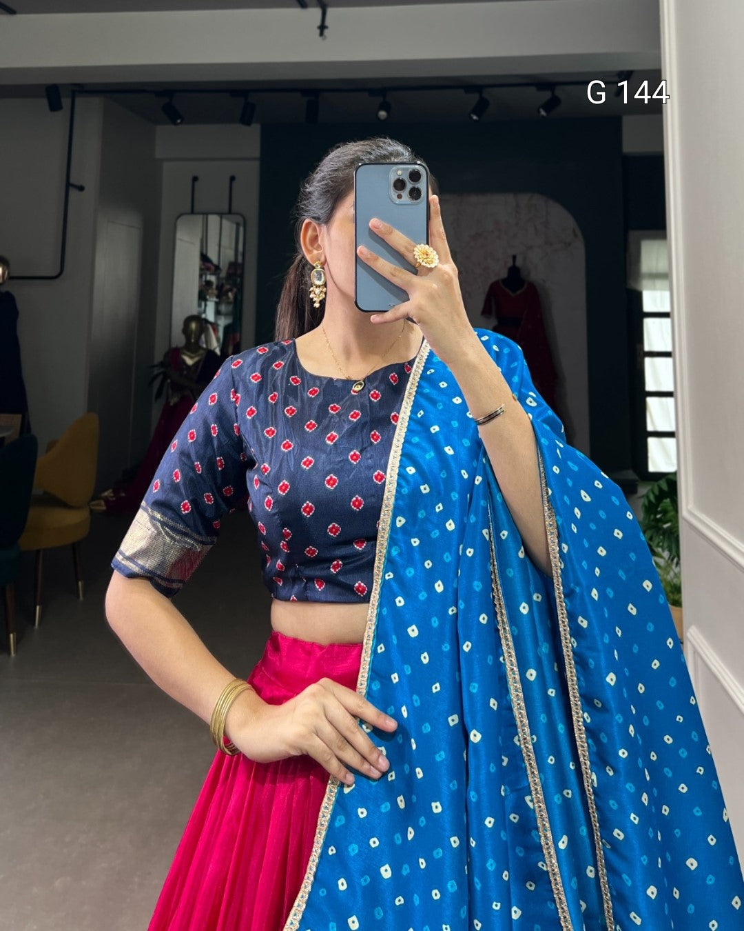 Person wearing a blue saree with white patterns and a pink blouse, taking a mirror selfie.