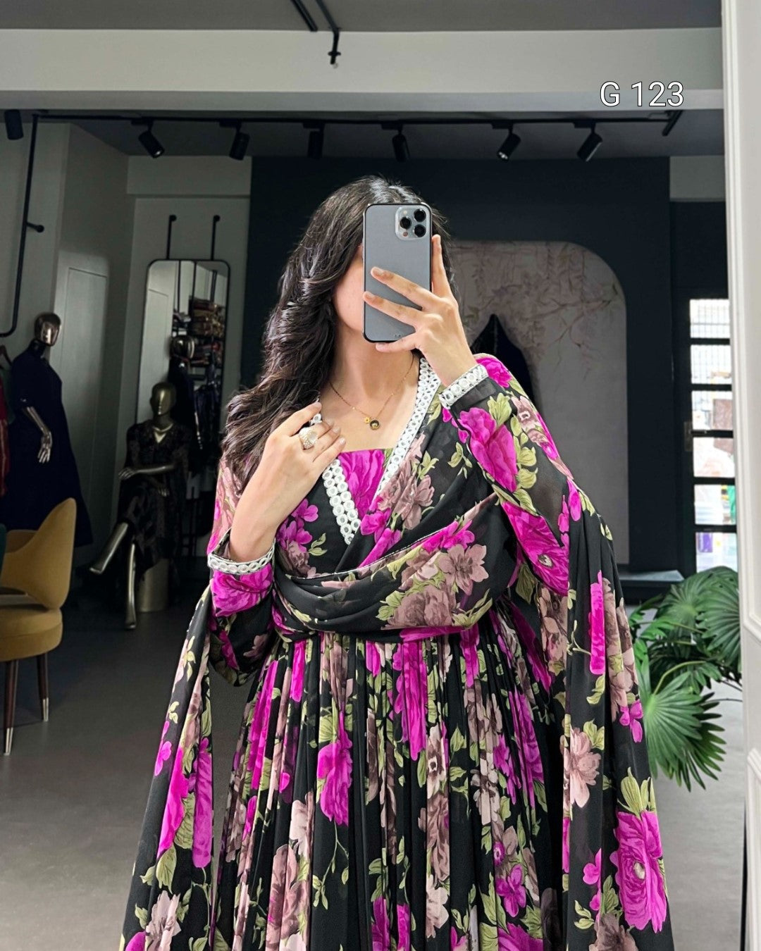 Person wearing a floral dress with pink and black colors in an indoor setting.