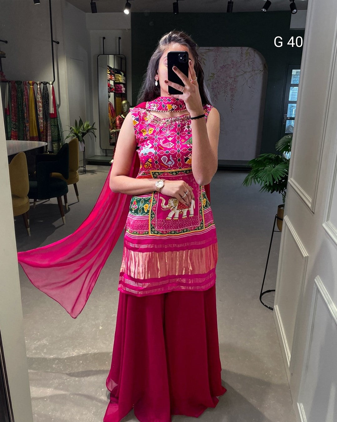 Person wearing a colorful traditional outfit with pink and multicolor patterns in an indoor setting.