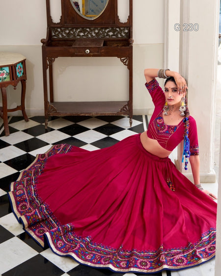 Woman in a vibrant red saree with intricate patterns in a room with checkered floor and wooden furniture.