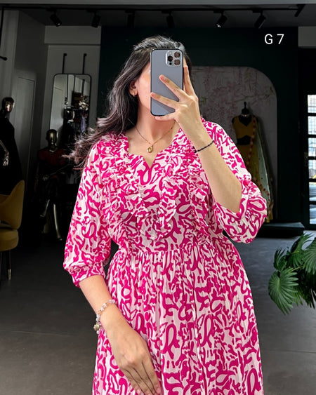 Woman taking a mirror selfie wearing a pink and white patterned dress in a store setting.