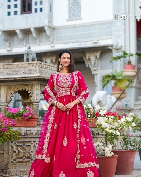 Woman in a red traditional outfit standing in front of an ornate building with flowers.
