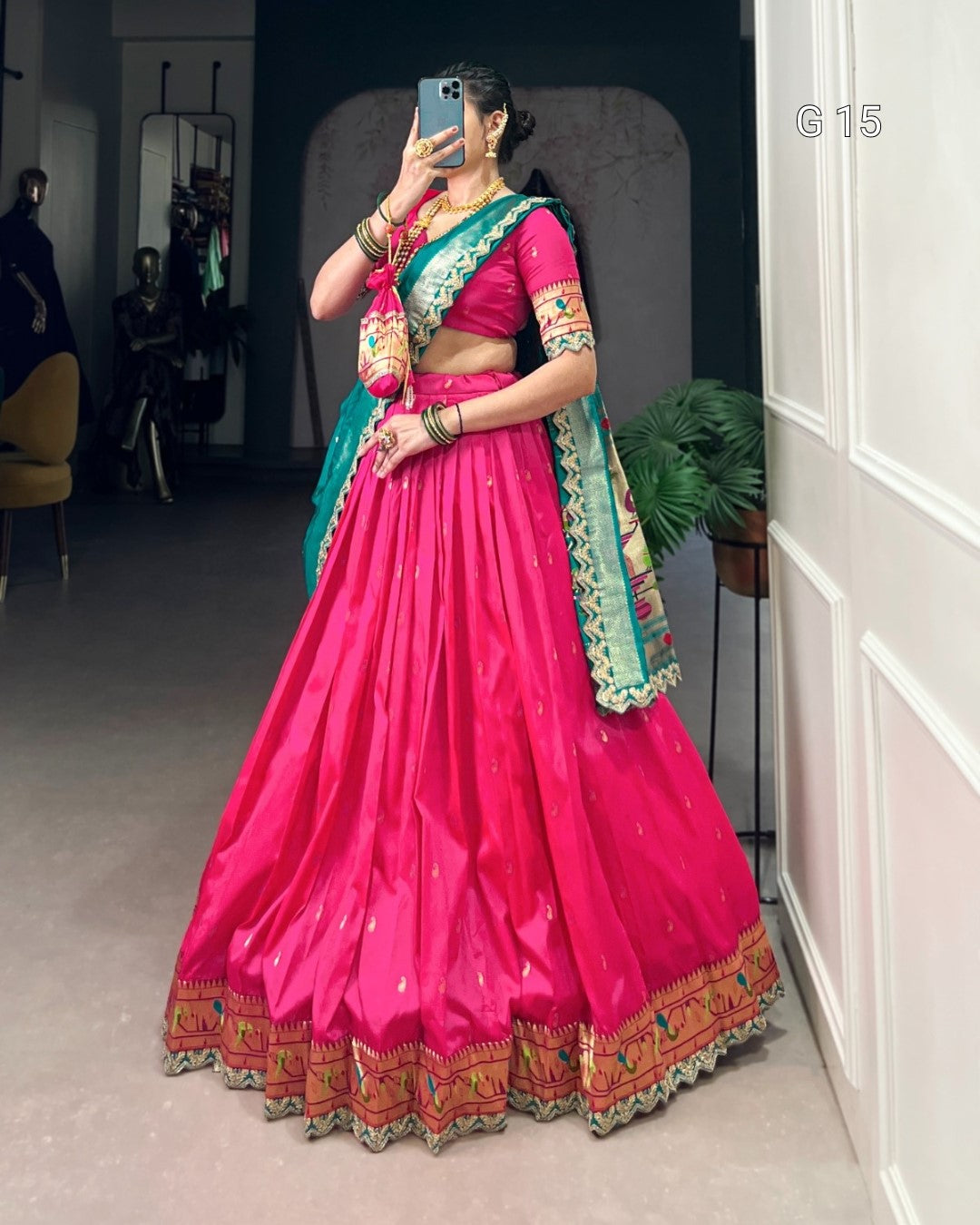 Person wearing a bright pink traditional outfit with green and gold accents, standing in a room.