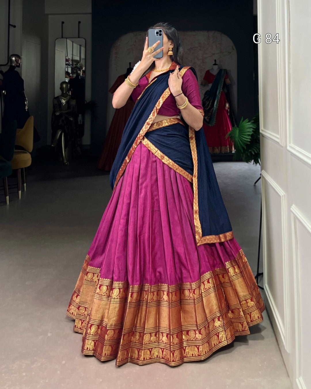 Person wearing a traditional outfit with a pink and blue saree in a room.