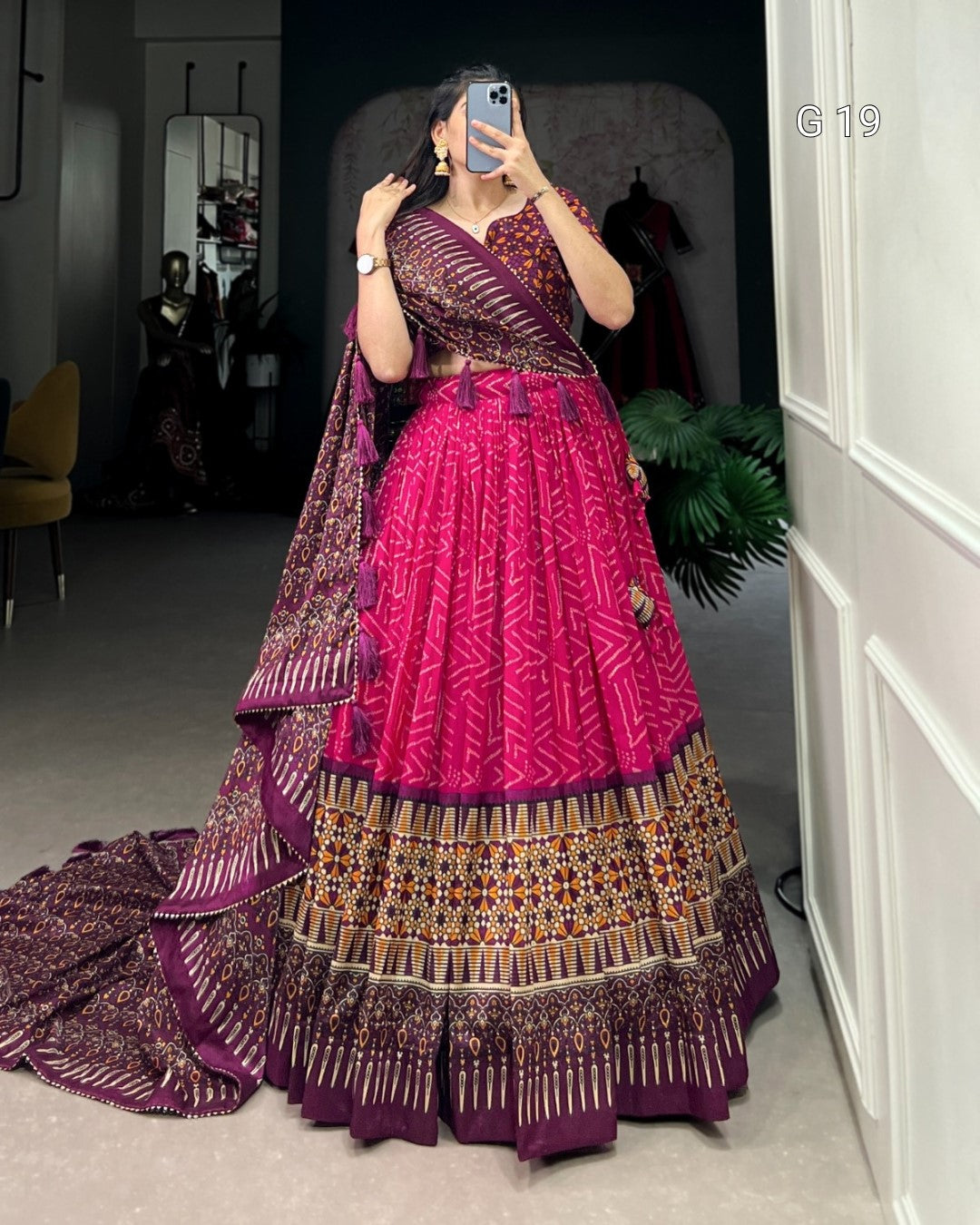 Person wearing a traditional pink and purple outfit with a matching dupatta, standing in a room.
