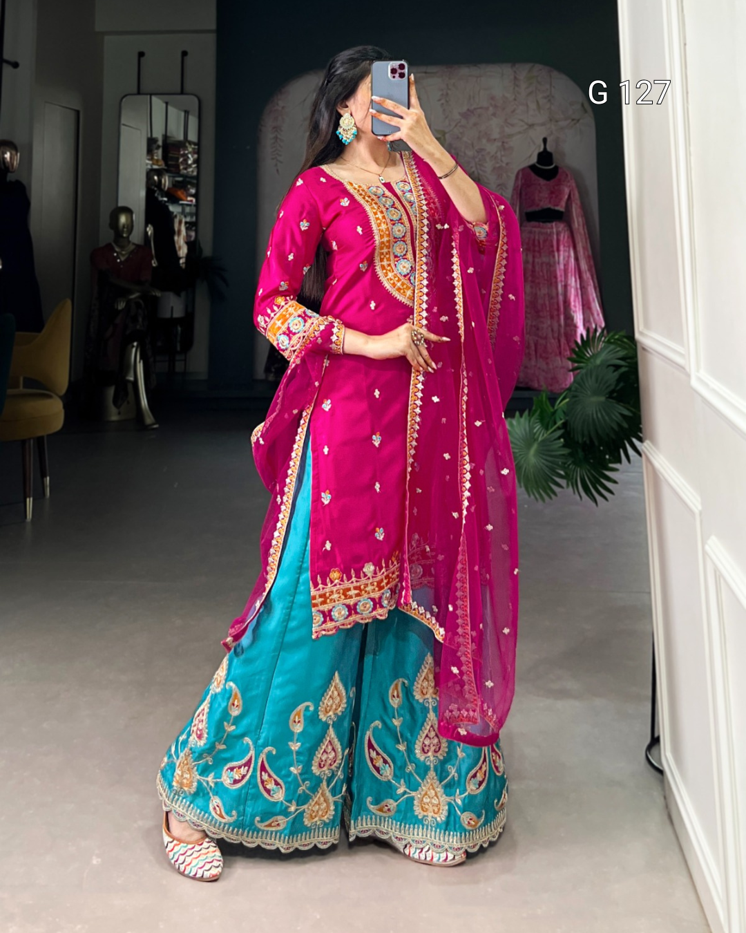 Woman wearing a traditional outfit with a pink dupatta and blue lehenga in a room.